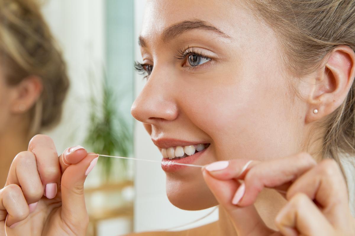 Young,Beautiful,Woman,Cleaning,Her,Teeth,With,Floss,In,Bathroom. Making Flossing Fun