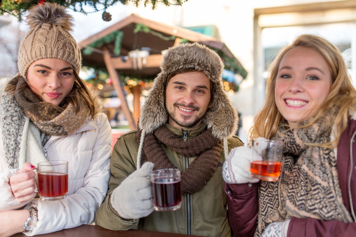 5 Holiday Foods that are Good for Your Teeth Three people enjoying warm drinks at outdoor winter market celebration